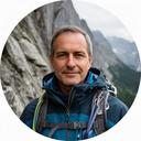 André Dubois vor einer alpinen Felswand mit Bergführerausrüstung
