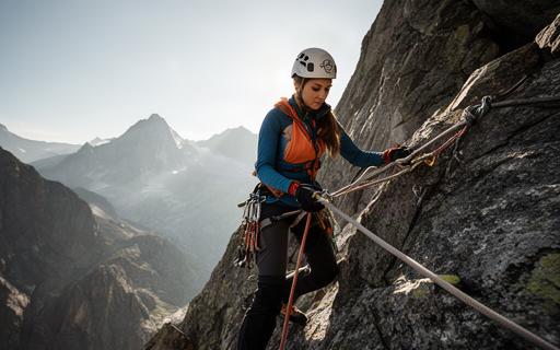 Bergsteigerin mit Helm und Seil an einer felsigen Alpinroute